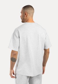 Camiseta gris de gran tamaño, hecha de una tela suave, con mangas cortas, un escote redondeado y un corte relajado. Presenta un diseño de espalda sin costuras.