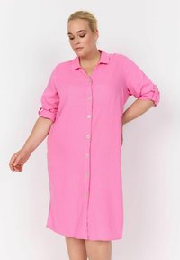 Abito rosa con colletto, maniche arrotolabili e taglio dritto. Realizzato in tessuto leggero, con bottoni frontali visibili.
