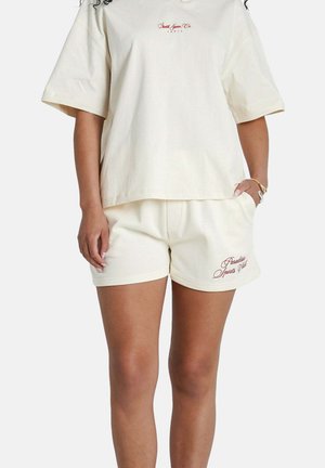 Crèmekleurig katoenen t-shirt met korte mouwen en geborduurd logo. Gecombineerd met bijpassende shorts met zijzakken en decoratieve stiksels.