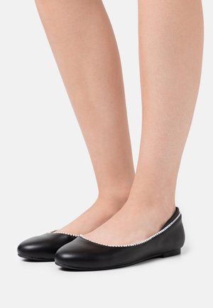 Ballerines noires en cuir avec un bout rond, ornées d'une bordure de perles contrastantes le long du bord supérieur et d'une semelle plate.