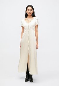 Hellcremefarbenes Midikleid mit kurzen Puffärmeln, Spitzenoberteil und vorderer Knopfleiste, mit kleinem Schlitz am Saum.