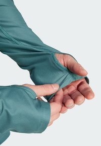 Leichte, türkisfarbene Langarmbekleidung mit Netzstruktur und Daumenlöchern. Verfügt über ein nahtloses Design und kontrastierende Nähdetails.
