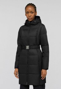 Svart dunjacka med markerad midja, hög krage, dragkedja framtill och fickor. Slät textur och quiltad design.