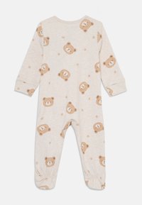 Einsie in cremefarben aus weichem Stoff, mit einem Allover-Druck von Teddybären und kleinen Sternen. Es hat lange Ärmel und gepuffte Knöchel.