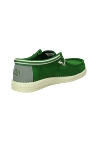 Scarpa slip-on in tela verde con un accento grigio, caratterizzata da una punta arrotondata, lacci elastici e una suola testurizzata. Il design include il marchio sul tallone.