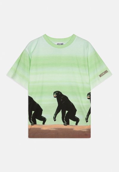 T-skjorte med grønn gradient bakgrunn og svarte sjimpanser som går over bunnen, med "Moschino"-logo på ermet.