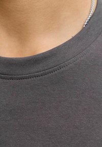 Grå bomulds t-shirt med rund hals og en glat tekstur, der har en ribbet krave og fine syninger ved halsudskæringen.