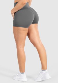 Grijze sportshorts met een hoge tailleband, een aansluitend ontwerp en een gladde textuur, gecombineerd met witte sportschoenen en sokken.
