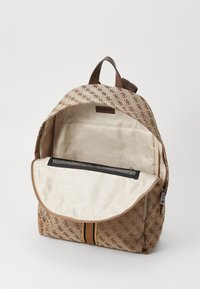 Sac à dos marron à motifs avec un intérieur beige, muni d'une poche zippée et d'une fermeture à rabat plate. Fabriqué en tissu au toucher lisse.