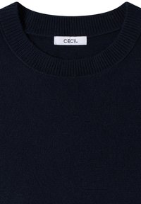 Pull en maille bleu marine foncé avec col rond côtelé et étiquette rectangulaire blanche portant l'inscription "CECIL" cousue à l'intérieur du col.