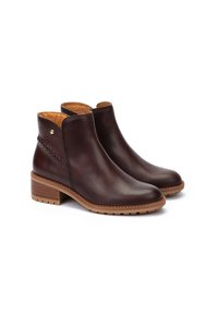 Botas de tobillo de cuero marrón con un acabado suave, un pequeño tacón y un detalle trenzado en el costado. Presentan un forro de cuero beige y una suela resistente.