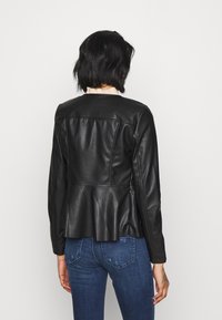 Giacca in pelle nera con un design posteriore plissettato e spalle strutturate, caratterizzata da una texture liscia e una silhouette aderente.