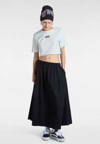 Lys mintfarvet cropped t-shirt med "VANS" logo, parret med en sort, flydende maxi nederdel og sorte sneakers med hvide snørebånd. Sort beanie-hat.