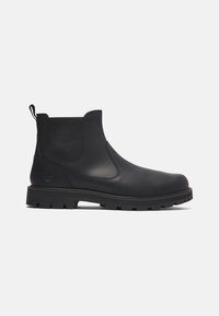 Bottine noire en cuir avec panneaux latéraux élastiques, languette de tirage, semelle épaisse à crampons et logo embossé près du talon.