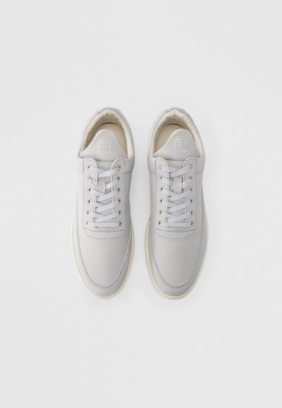 Αθλητικά παπούτσια από ανοιχτό γκρι δέρμα με στρογγυλή μύτη, έξι οπές για κορδόνια και επίπεδα κορδόνια. Σόλα από ελαστικό χρώματος κρέμας, με ελάχιστο λογότυπο στη γλώσσα.