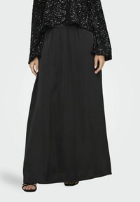Jupe maxi noire en tissu lisse, dotée d'une taille élastique pour le confort. La jupe descend jusqu'aux chevilles, offrant une silhouette fluide.