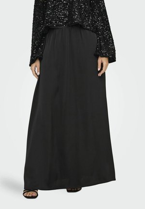 Jupe maxi noire en tissu lisse, dotée d'une taille élastique pour le confort. La jupe descend jusqu'aux chevilles, offrant une silhouette fluide.