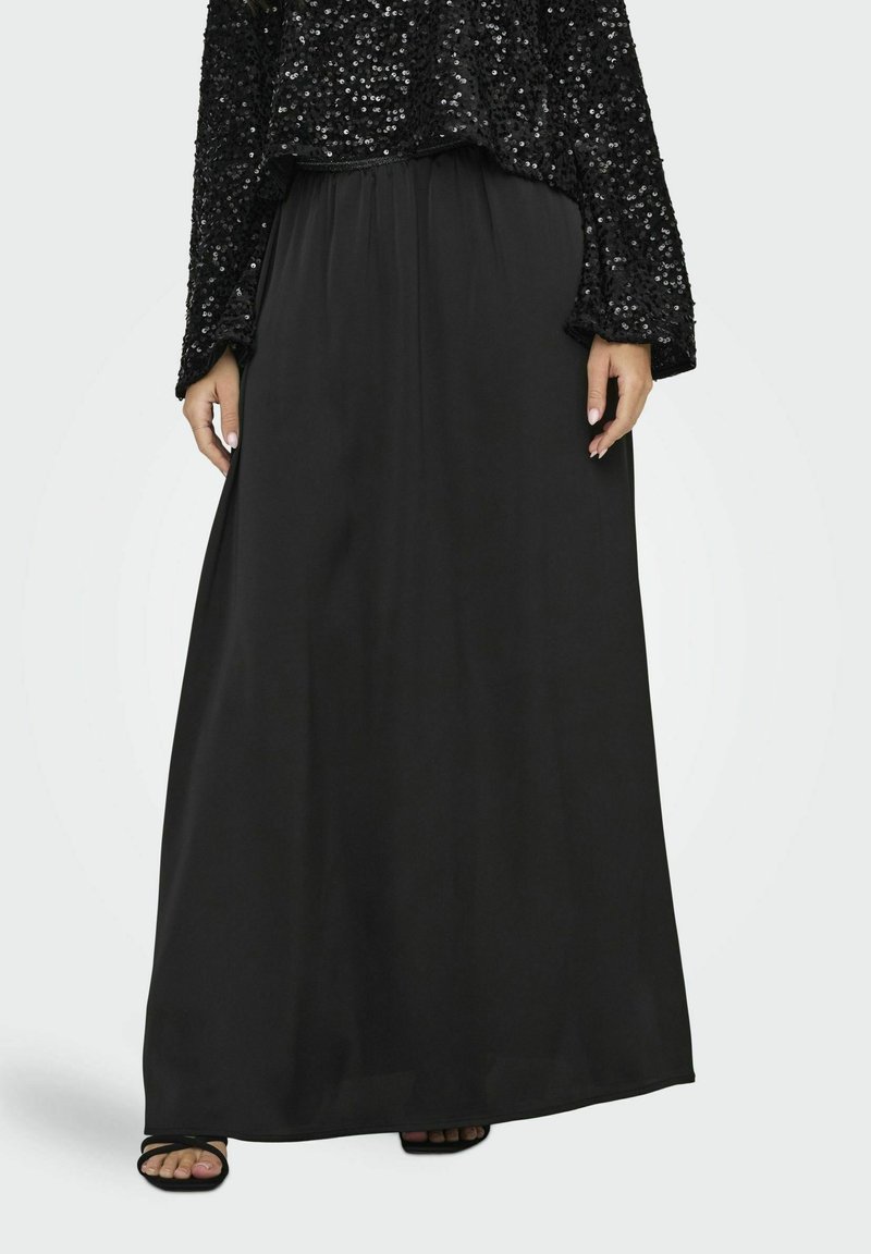 Jupe maxi noire en tissu lisse, dotée d'une taille élastique pour le confort. La jupe descend jusqu'aux chevilles, offrant une silhouette fluide.