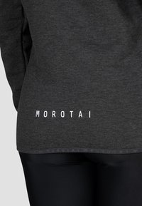 Dunkelgrauer Hoodie mit weicher Textur. Mit weißem "MOROTAI"-Logo am Saum, lockerer Passform und Rundhalsausschnitt.