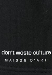 Black fabric featuring white text. Text reads "don't waste culture" above "MAISON D'ART." Smooth texture with ribbed design.