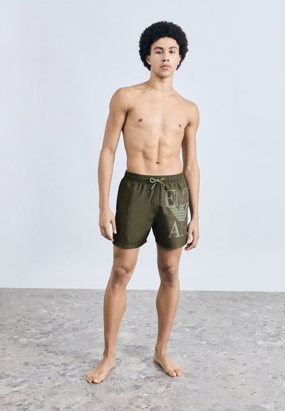 Olíva zöld fürdőnadrág elasztikus derékpánttal és húzózsinórral. Nagyméretű logófelirat a bal oldalon. Könnyű anyag és egyszerű dizájn.