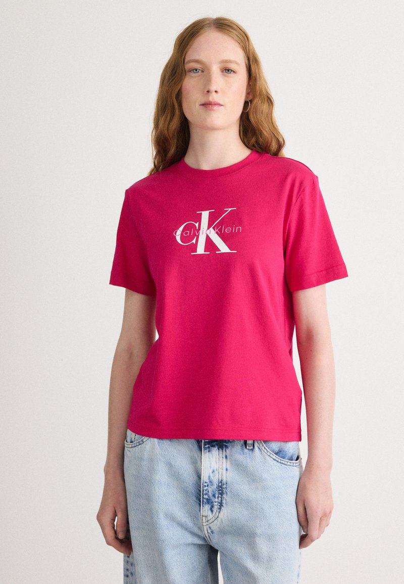 Camiseta de algodón fucsia con mangas cortas y cuello redondo, con un logo blanco de Calvin Klein impreso en la parte delantera.