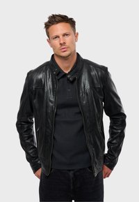 Chaqueta de cuero negra con cuello tipo solapa, cierre de cremallera y ajuste Slim. Presenta costuras en contraste y bolsillos laterales. Acabado texturizado.
