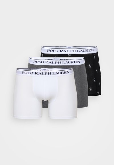 Drie paren mannenboxershorts: wit, grijs en zwart met een patroonlogo. Elk heeft een elastische tailleband met "POLO RALPH LAUREN."