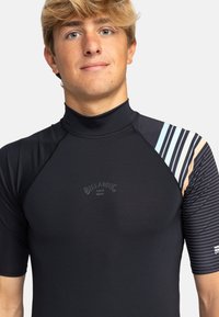 Svart kortärmad rash guard gjord av stretchmaterial, med hög hals och flerfärgade randiga detaljer på vänster axel.