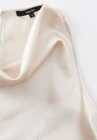 Top con collo a cowl in tessuto testurizzato bianco sporco, caratterizzato da un sottile motivo a griglia e orlo cucito. Etichetta del marchio 'someday.' taglia 36 visibile.