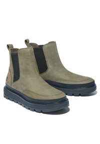 Olivgrüne Wildleder-Chelsea-Stiefel mit schwarzen elastischen Seiteneinsätzen, strukturierten Oberflächen und robusten grauen Gummisohlen, mit Ziehlaschen hinten.