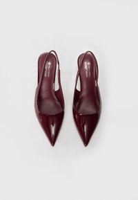Talons slingback en cuir verni bordeaux avec un design à bout pointu, texture lisse et une image de marque minimaliste sur la semelle intérieure.