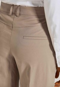 Beige broek met een gladde textuur, voorzien van een vlakke voorkant, een tailleband en een enkele achterzak met een rechthoekige flap.