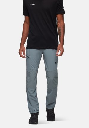 Pantalons d'extérieur gris clair avec poches fonctionnelles, panneaux aux genoux et un logo. Associés à une chemise noire à manches courtes. Tissu léger et durable.