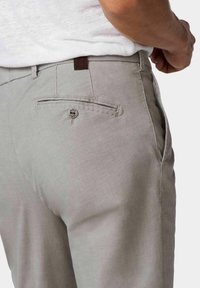Pantalons tissés gris avec une finition texturée, une poche arrière avec une fermeture à bouton et un subtil accent marron sur la ceinture.