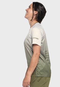Lightweight, textured athletic shirt with a gradient from gray to green. Features a crew neck and logo on the sleeve. Text on the side.