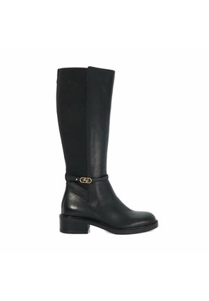 Botte en cuir noire montant jusqu’au genou avec talon bloc bas et détail de bride à boucle dorée autour de la cheville, vue de côté gauche sur fond blanc.