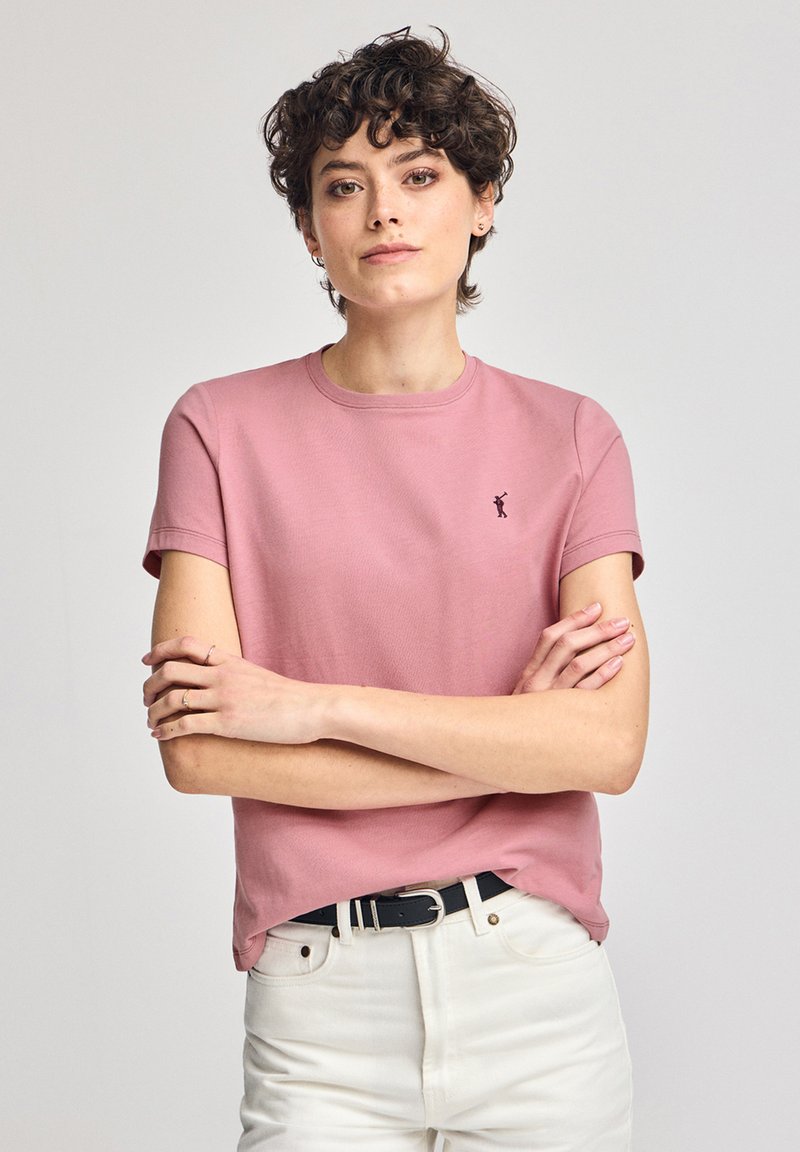 Camiseta de manga corta y escote redondo en algodón de color rosa claro con un acabado texturizado y un pequeño detalle de logo negro en el lado izquierdo del pecho.