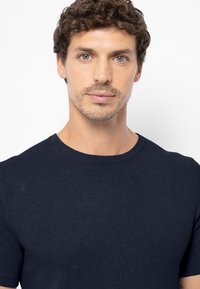 Marineblauwe T-shirt met korte mouwen, geribbelde textuur, ronde hals, getailleerd ontwerp, lichtgewicht stof, eenvoudig zonder patronen of accenten.