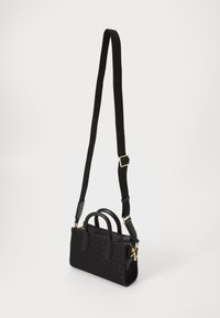 Black handbag made of textured material, featuring dual handles, adjustable crossbody strap, and gold hardware accents.