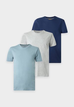 Homme debout pieds nus portant un t-shirt à manches courtes bleu marine assorti et un short sur un fond blanc uni.