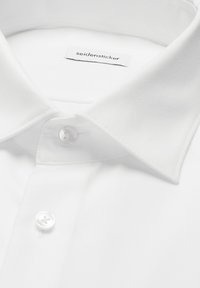 Col de chemise blanche et boutons supérieurs avec étiquette de marque "seidensticker" cousue à l'intérieur du col.