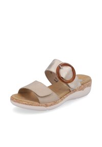 Sandale beige avec deux bride ; l'une est lisse, l'autre a un accent circulaire marron. Dotée d'une semelle texturée imitant le liège et d'une base blanche.