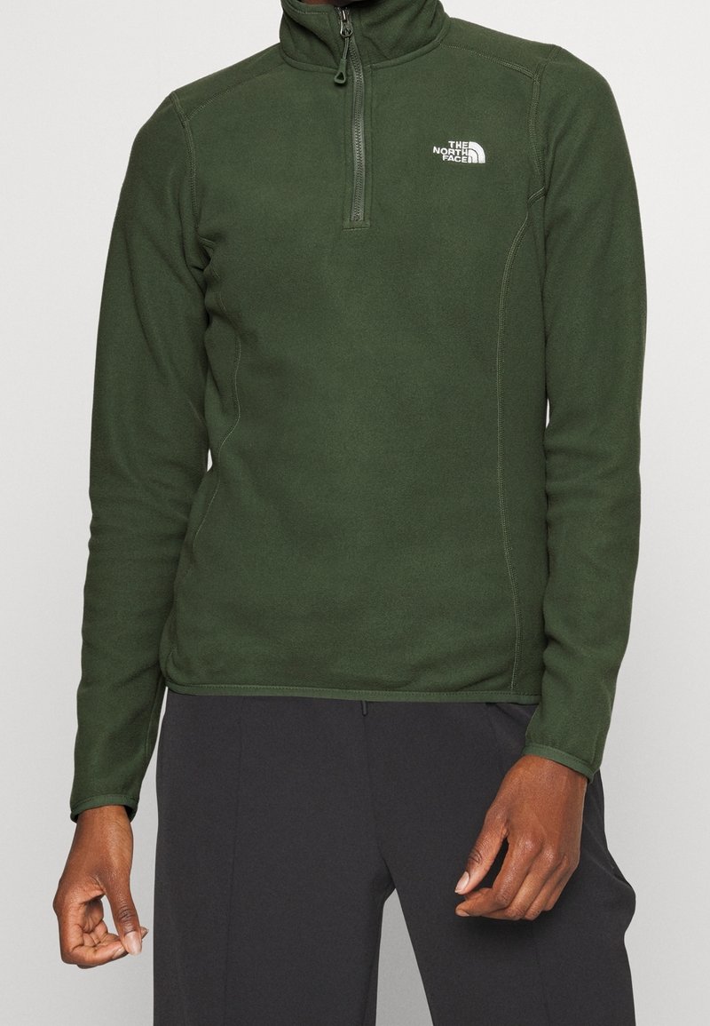 Pullover in fleece verde scuro con collo a mezza zip e logo The North Face. Presenta maniche lunghe e una texture liscia con dettagli cuciti.
