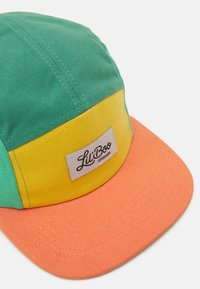 Baseball cap with a green top, yellow midsection, and orange brim. Features a fabric tag with the brand name "Lil' Boo" in black.