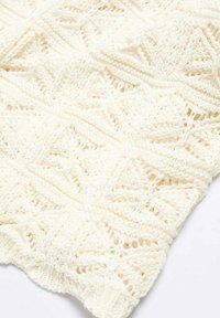 Écharpe en tricot de dentelle blanc cassé, présentant un motif géométrique avec des sections ajourées et texturées, un tissu doux et un bord incurvé.