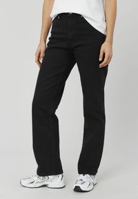 Jean en denim noir avec une coupe droite ; dispose d'un design classique à cinq poches et de passants de ceinture. Assorti avec des baskets blanches.