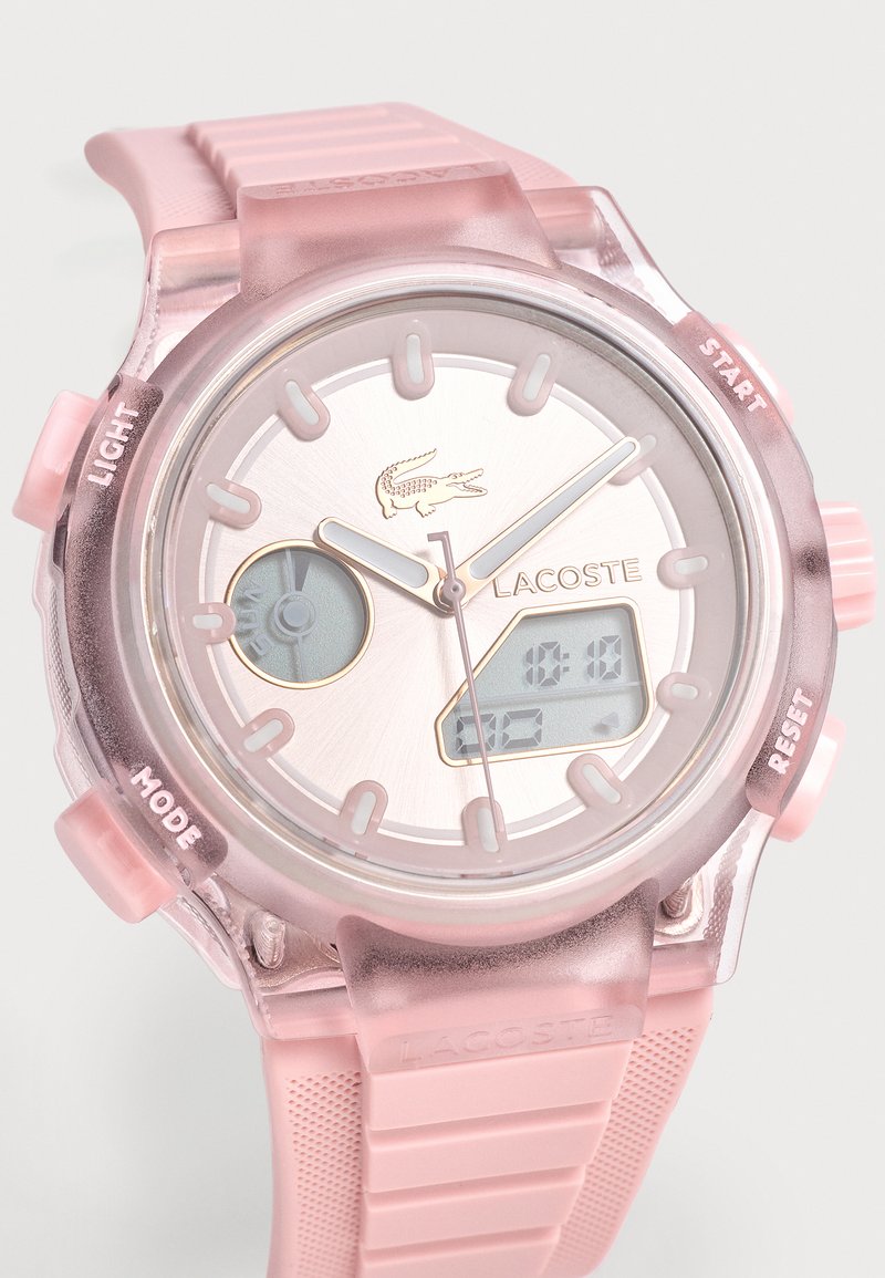 Pinkfarbene Lacoste Armbanduhr mit analoger und digitaler Anzeige, Kautschukarmband und beschrifteten Tasten für Licht, Start, Modus und Zurücksetzen.