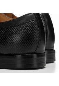 Černé kožené boty s tkanou texturou, hladkým povrchem a nízkým sloupkovým podpatkem. Detailní prošití podél okrajů zdůrazňuje design.