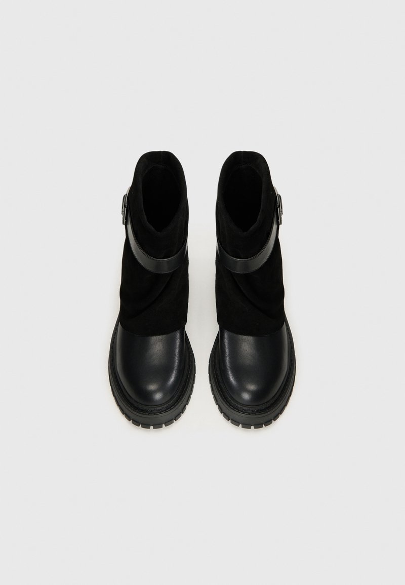 Schwarze Knöchelstiefel aus einer Kombination von glattem Leder und weichem Wildleder, mit einer Schnallenakzent und einer robusten Gummisohle.